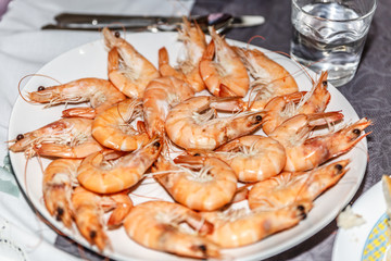 Freshly cooked prawns ready to eat next to a glass of water