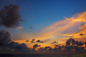 Orange sunset over sea, with dark clouds