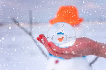 Cute smiling snowman in glass ball, sunny day, happy winter concept