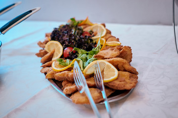 Fesh fried wiener schnitzels with lemon decoration and green salad