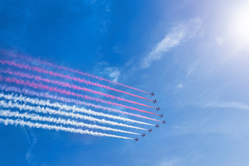 Airplanes leaving red white streaks in colors of Monaco flag in the sky air show