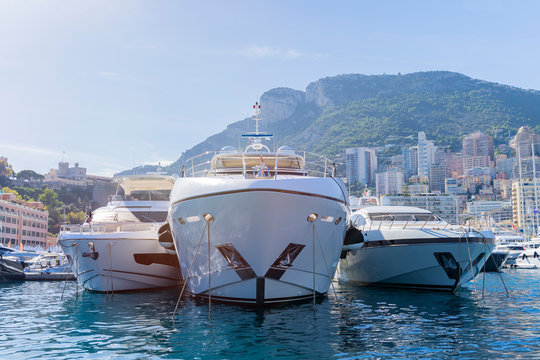 Three yachts moored in Monaco harbour  with Monaco landscape on a background