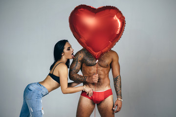 Man in red panties and women with a red heart balloon - Valentine symbol. Lover and heart attack....