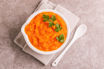 Bright tasty pureed carrot soup in clay bowl with napkin