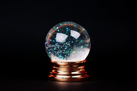 Beautiful snow ball with snowfall inside over black background.