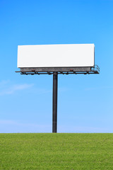 Tall Billboard sign a grassy hill in the foreground and blue sky in the background