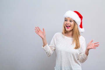 Happy woman with a Santa hat on a gray background