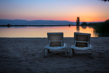 Fototapeta na wymiar sunbeds together with sun umbrella on the beach in a sunset