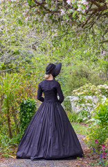 Fototapeta premium Victorian woman in black ensemble outdoors