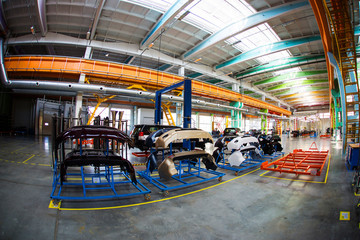 Automotive Plant. Disassembled cars are in a large bright workshop.