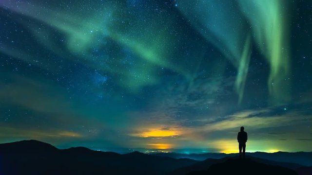 The man standing on the mountain on the northern light background. time lapse