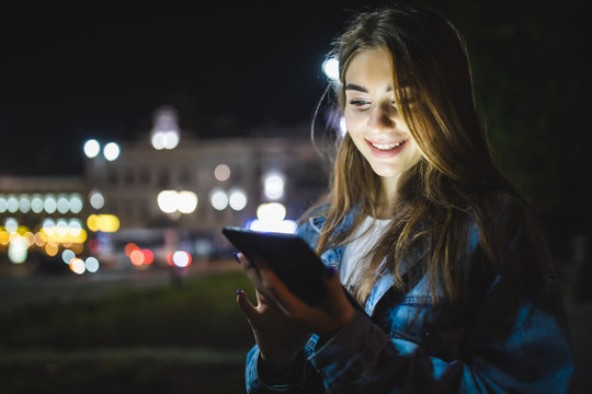 Attractive Woman Using Digital Tablet On City Street At Night