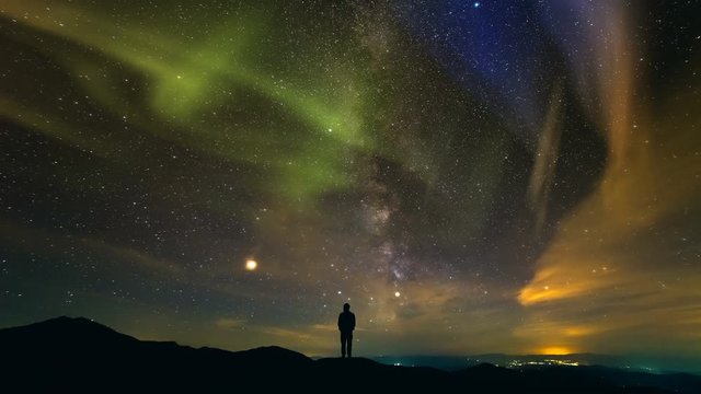 The man standing on a background of the city with a northern light. time lapse