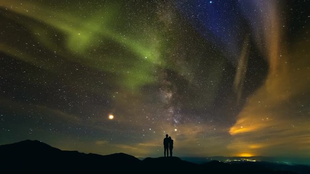  The couple standing on a background of a city with a northern light. time lapse