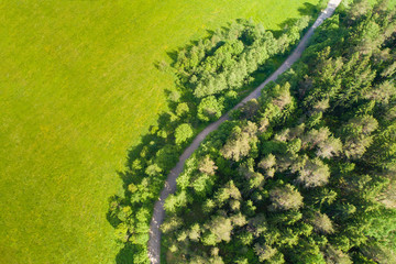 Forest road from above. The road passes through the field. Dirt road with a bend.