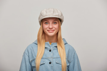 Pretty lovely young blonde girl with long hair down, looking glad, smiling, wearing oversize denim...