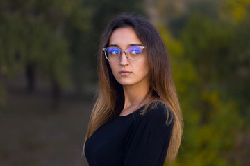 Beautiful portrait of a girl with glasses against the background of the forest, The concept of sexual teacher