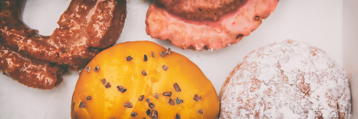 Donuts box panorama banner. Boston cream passion fruit doughnut, berry jelly filled berliner, glazed cruller fried donut pastry. Cake donut header background.