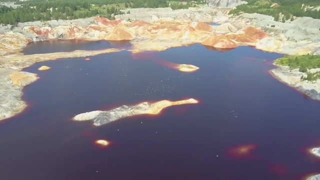 flycam moves close to blue pond water on clay pit with birds