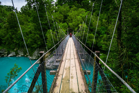 Fototapeta The wooden swing bridge in the green nature.