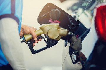 Hand refilling the car with fuel at the gas station.