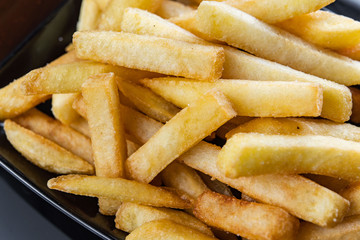 French fries close-up in black plate with sauce.