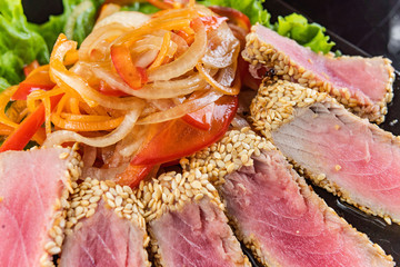 Close Up Still Life of Roasted Tuna Steaks Crusted with Herbs and Sesame Seeds on Dark Gray Surface