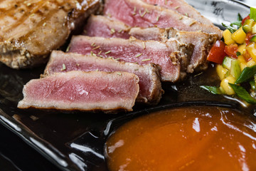 Close Up Still Life of Roasted Tuna Steaks Crusted with Herbs and Sesame Seeds on Dark Gray Surface