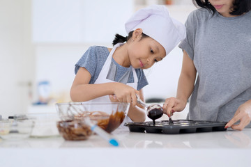 Child and mother preparing chocolate dough