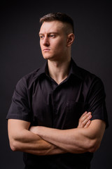 Young handsome businessman with arms crossed against gray background