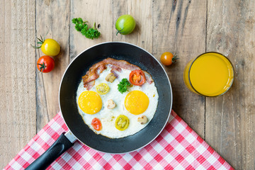 Fried eggs in frying pan with cherry tomatoes