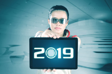 Futuristic woman showing number 2019 on tablet