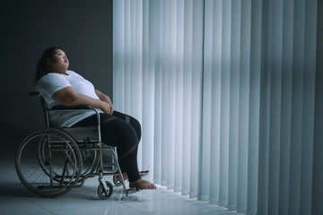 Lonely obese woman sitting in the wheelchair