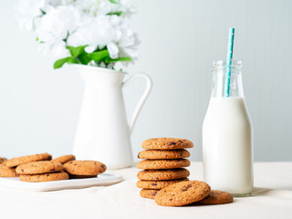 Chocolate oatmeal cookies and milk in bottle, healthy snack. Light background, grey light wall