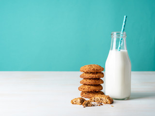 Oatmeal cookies with flax seeds and milk in bottle, healthy snack. Light background, bright blue wall