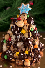 Christmas croquembouche cake made with profiteroles decorated chocolate icing and sweets, a gingerbread cookie snowflake on the top