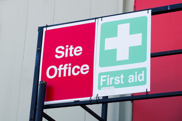 First aid site office sign on construction building door railing for workplace health and safety...