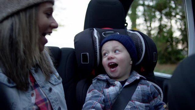 Mom Sits In Back Seat Of Jeep With Top Off, She Whispers A Secret To Her Little Boy, He Makes A Surprised Face And They Laugh, Slow Motion