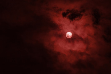 Full moon covered red clouds in the night sky
