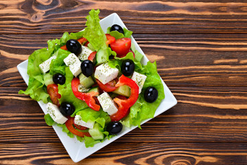 Greek salad on a wooden background. Space for text or design.