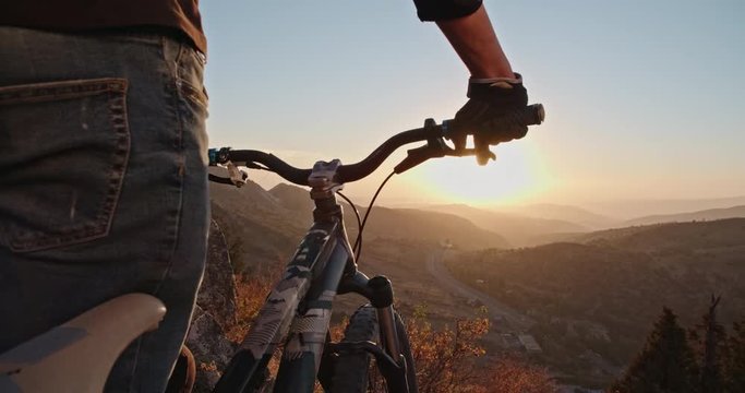Cool mountain biker standing on edge of a mountain, ready to ride down - recreational pursuit, getting away from it all 4k