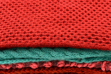 Knitted red, orange, green scarves. Collection of woolen clothes.