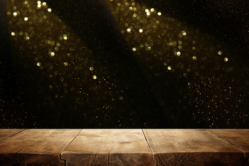 rustic wooden table in front of glitter black and gold bokeh lights.