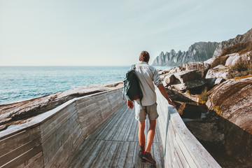 Man tourist walking on beach wooden bridge with backpack Traveling in Norway heathy lifestyle adventure concept vacations outdoor