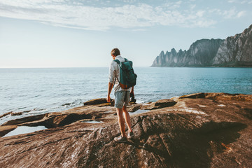 Man traveler walking alone on beach traveling vacations in Norway lifestyle outdoor Okshornan peaks landscape