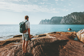 Fototapeta na wymiar Travel man standing on Norway seaside with backpack adventure lifestyle summer vacations outdoor traveler enjoying Okshornan peaks view