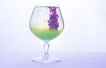 Colorful paint in water in a crystal glass on a white background