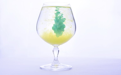 Colorful paint in water in a crystal glass on a white background