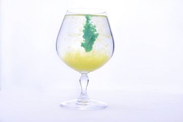 Colorful paint in water in a crystal glass on a white background