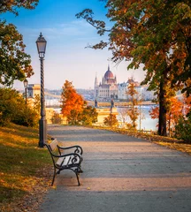 Poster Budapest, Hungary - Romantic sunrise scene at Buda district with bench, lamp post, autumn foliage, Szechenyi Chain Bridge and Parliament at background © zgphotography